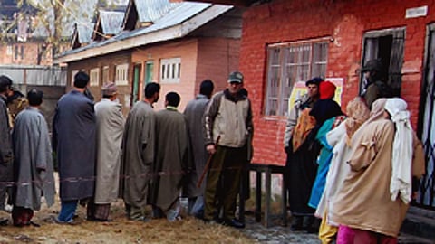 People wait to cast their vote in a queue outside a polling station in J&K.