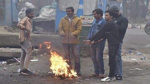People around a bonfire to protect themselves from winter on a coldest and foggy morning in New Delhi,