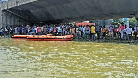 Residents of apartments take shelter under a flyover following heavy rain