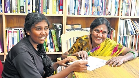 A woman being taught to read and write Kannada at the library at Neelasandra GP