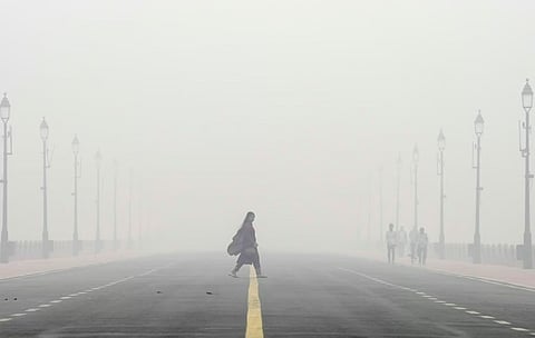 A woman crosses the Kartavya Path amid low visibility due to smog as air quality remains in 'severe' category, in New Delhi, Monday, Nov. 18, 2024.