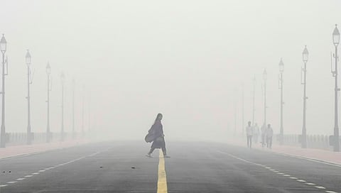 A woman crosses the Kartavya Path amid low visibility due to smog as air quality remains in 'severe' category,