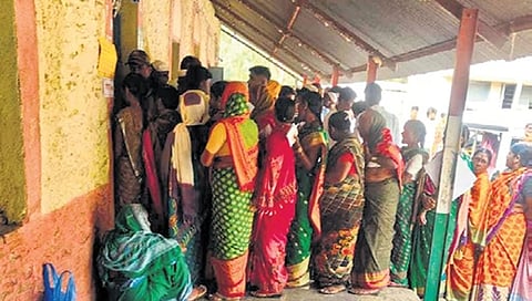 Voters wait outside a polling booth at a border village in Umadi Jatt taluk