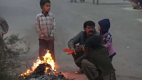 People near a bonfire during a cold and foggy winter morning, in New Delhi