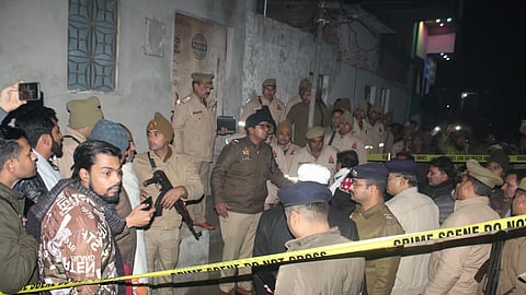 Police personnel conduct an investigation after at least five members of a family were found dead