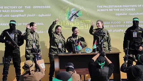 Israeli female soldier hostages wave at a Palestinian