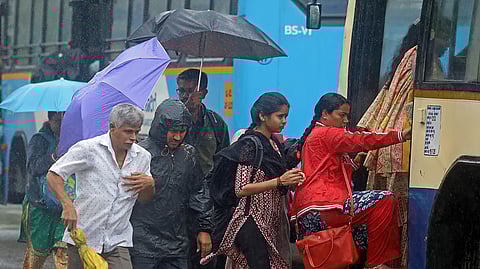Rain shower as they leave for their work on Kengeri ring road in Bengaluru