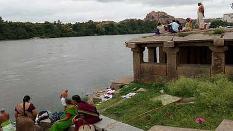 Tourists at Tungabhadra river in Hampi where Purandaradasa Mantap was submerged due to flooding.