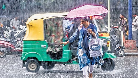 A woman cautiously crosses a busy road near High Grounds Circle, impeded by rain which has lashed Bengaluru over the last few days.