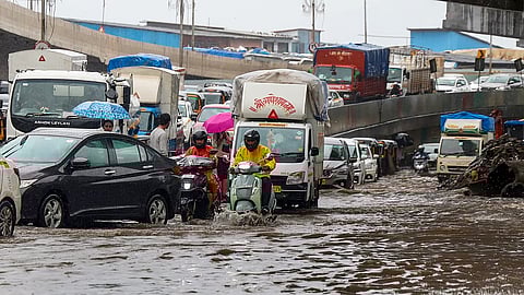 Commuters wade through a waterlogged road amid rainfall, in Mumbai