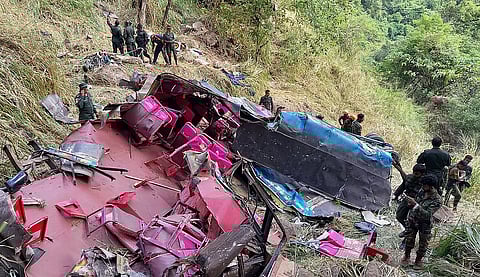 Soldiers and rescue workers stand by the debris of a passenger bus after it plunged into a precipice in Wellawaya, Sri Lanka.