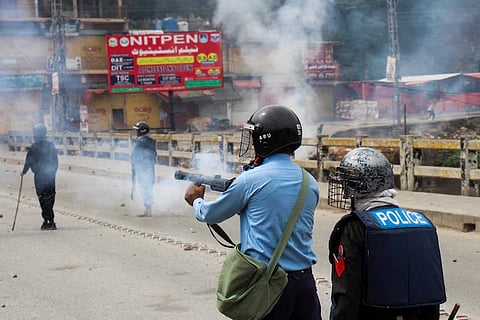 A police officer fires tear gas to disperse the protesters