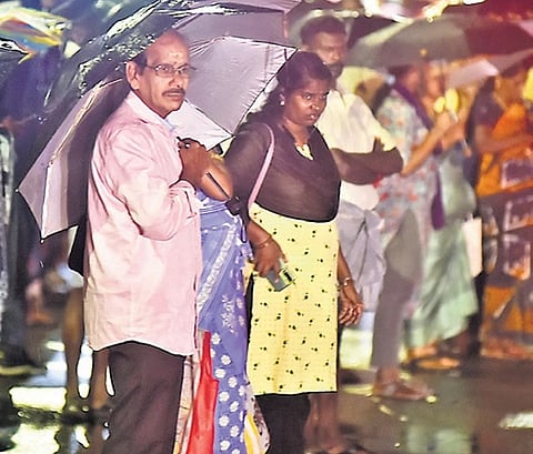 People wait for buses at Vadapalani amid the rains in Chennai