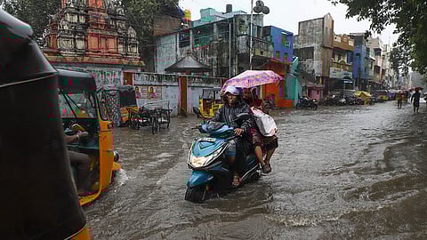 People wade through waterlogged road amid heavy rainfall in the wake of Cyclone Ditwah, in Chennai