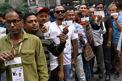 Voters wait in line outside a polling center to cast their ballots during the national parliamentary elections in Dhaka, Bangladesh