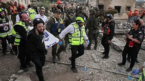 Emergency personnel carry a body at the site