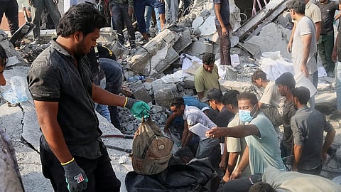 A man hold a children's backpack as rescue workers
