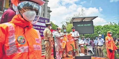 ಪೊಲೀಸರಿಗೆ ರೇನ್ ಕೋಟ್ ವಿತರಿಸುತ್ತಿರುವ ಸಚಿವ ಬೊಮ್ಮಾಯಿ