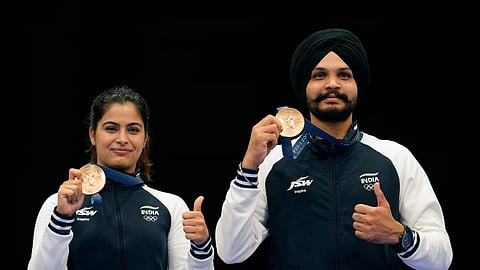 India's Manu Bhaker, left, and Sarabjot Singh pose for a photograph after winning the bronze medal in the 10m air pistol mixed team event at the 2024 Summer Olympics, Tuesday, July 30, 2024