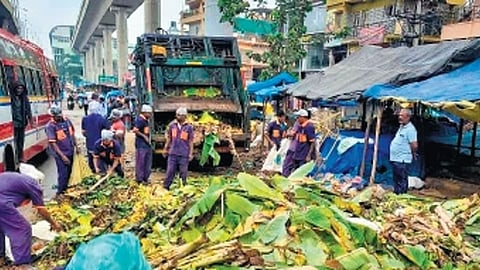 BBMP workers clear waste generated during the Dasara festival at a market