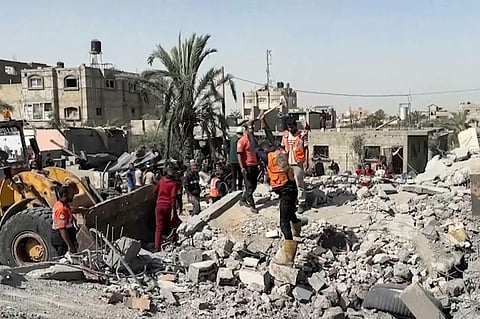 Palestinians check a building destroyed by Israeli airstrikes in the city of Khan Younis, southern Gaza Strip