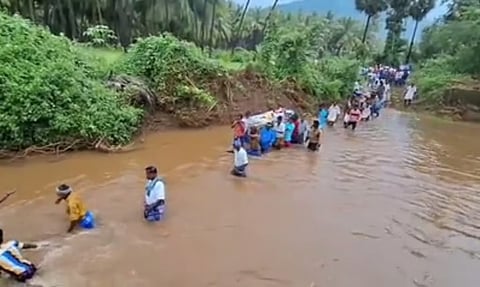 Villagers taking the mortal remains of elderly man across the river for burial in Natham in Dindigul district.(Photo | Express)