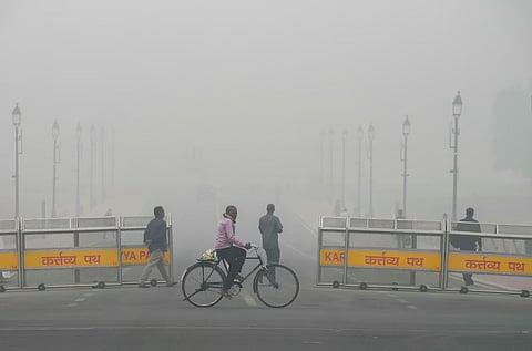 A man cycles near the India Gate amid low visibility due to smog as air quality remains in 'severe' category, in New Delhi, Monday, Nov. 18, 2024.