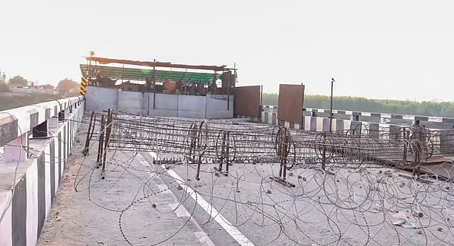 Concertina wire barricades are placed on a bridge at the protest site at Shambhu Border before the start of farmers march towards Delhi