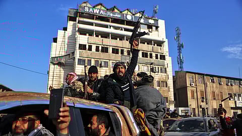 Syrian rebel fighters celebrate near the Clock Tower in Homs
