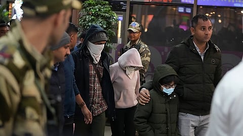 Indian police officials escort immigrants, wearing mask, deported from the United States, who were among those who arrived in a U.S. military plane Wednesday in Amritsar, upon their arrival at the Ahmedabad airport in India