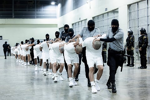 In this photo provided by El Salvador's presidential press office, prison guards transfer deportees from the US, alleged to be Venezuelan gang members, to the Terrorism Confinement Center in Tecoluca, El Salvador.