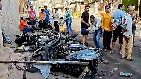 People gather near charred remains of two-wheelers in the aftermath of violence that erupted on Monday, in Nagpur.
