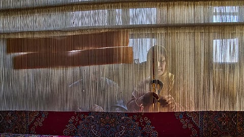 Shameema and her husband, Mohammad Yousaf Dar, weave a Kashmiri hand-knotted carpet at their home in Srinagar on April 15, 2025.