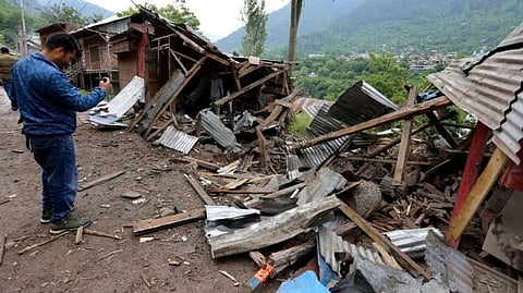 A man uses his mobile phone to film debris of shops damaged by cross-border shelling in Lagama village near the Line of Control (LoC), in Kashmir's Baramulla district, on May 9, 2025. 