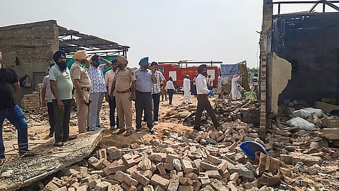 Police personnel and others stand at a firecracker manufacturing and packaging unit 