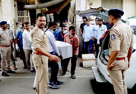 Hospital staff carry a coffin to load inside a vehicle outside the postmortem room at a hospital, in Ahmedabad, June 13, 2025.