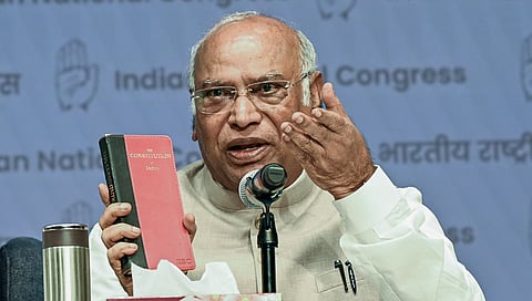Congress President Mallikarjun Kharge speaks while displaying a copy of the Constitution during a special briefing, at Indira Bhawan in New Delhi on Wednesday. 