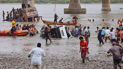 Rescuers and locals look for survivors after several vehicles fell into a river following the collapse of a portion of a bridge in Mujpur.
