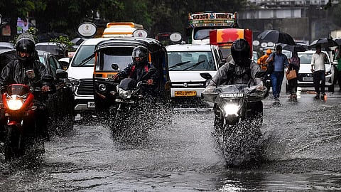 Commuters wade through a waterlogged road amid rainfall, in Mumbai, Monday, Aug. 18, 2025.