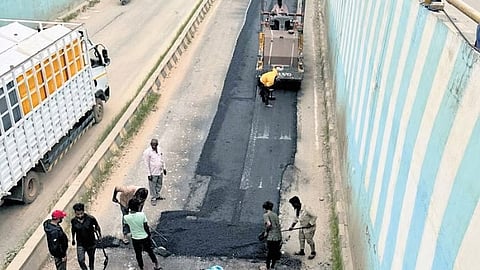 Civic workers fix a pothole-riddled stretch of road at an underpass in Bengaluru.