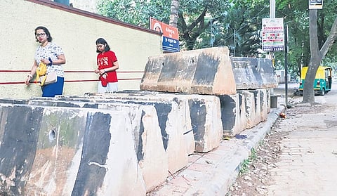 Pedestrians squeeze through concrete blocks placed on a footpath along 8th Main Road in Malleswaram on Thursday. 
