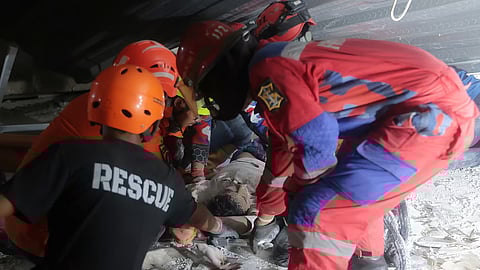 Rescuers pull out a survivor from a collapsed building at an Islamic boarding school in Sidoarjo, East Java, Indonesia