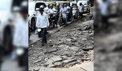 A pedestrian is forced to squeeze between passing vehicles and a dug-up footpath near the GBA head office at Hudson Circle on Monday.