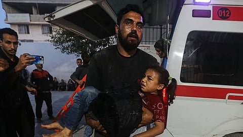 A Palestinian man carries a wounded girl into al-Shifa Hospital