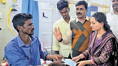 Dharwad DC Divya Prabhu hands over a cheque for Rs 5 lakh to Hanumantappa Doddamani, father of Vivekanand, at a private hospital in Hubballi on Tuesday.