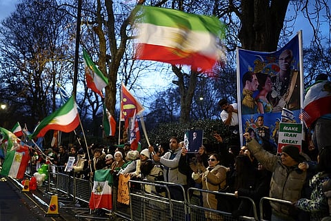 Anti-Iranian regime protesters wave Iranian flags during a gathering outside the Iranian Embassy, central London