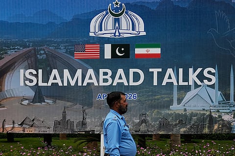 A police officer walks past a billboard regarding the United States and Iran negotiations, outside a media facilitation center in Islamabad, Pakistan