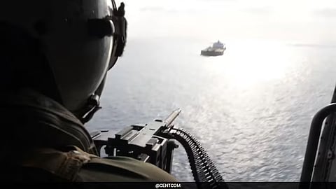 US soldier points a heavy-calibre machinegun at a vessel in the waterway near Iran