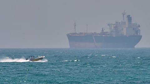 A boat sails past a tanker anchored in the Strait of Hormuz off the coast of Qeshm Island, Iran, Saturday, April 18, 2026.