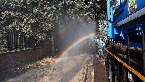 ಮರವೊಂದಕ್ಕೆ ಪೈಪ್ ಮೂಲಕ ನೀರು ಹಾಯಿಸುತ್ತಿರುವ ಕಾರ್ಮಿಕ